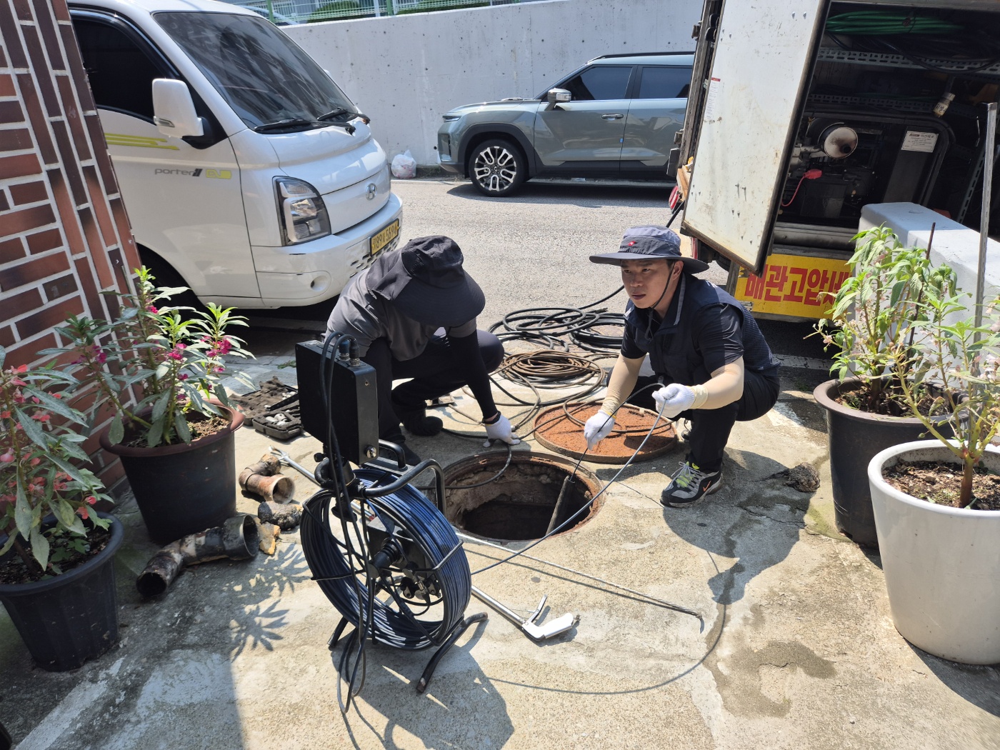 지상 주차장 맨홀에서 내시경 장비로 작업하는 사진