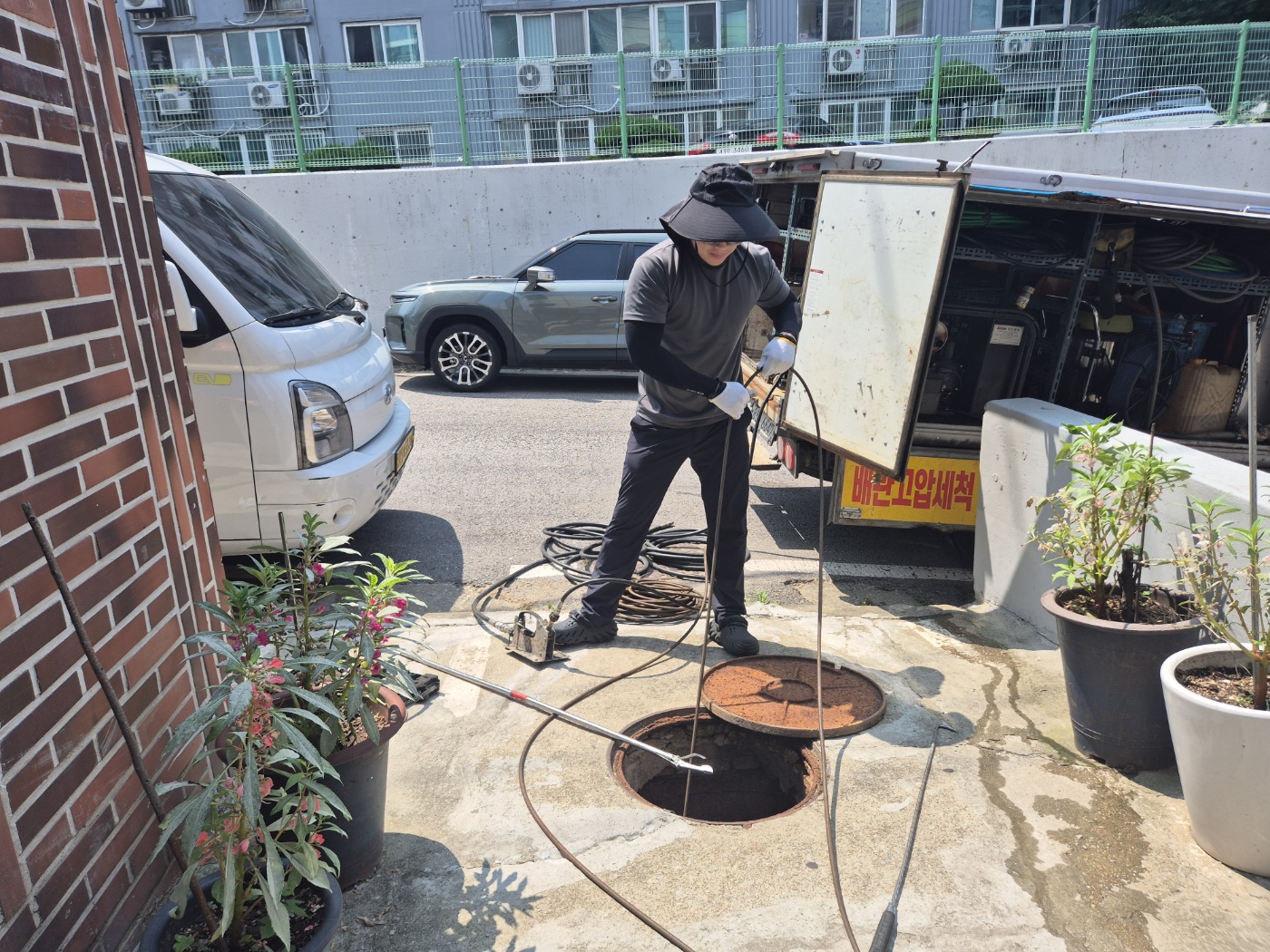 배관고압세척 차량 앞에서 맨홀 작업을 진행하는 사진