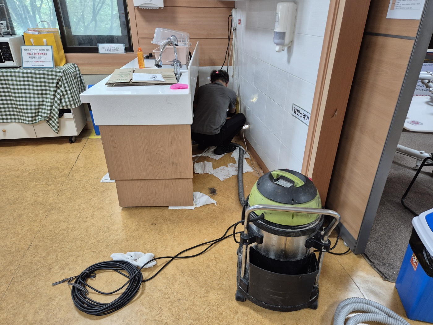 병원 개수대 하부장 안쪽 배관을 확인하는 사진