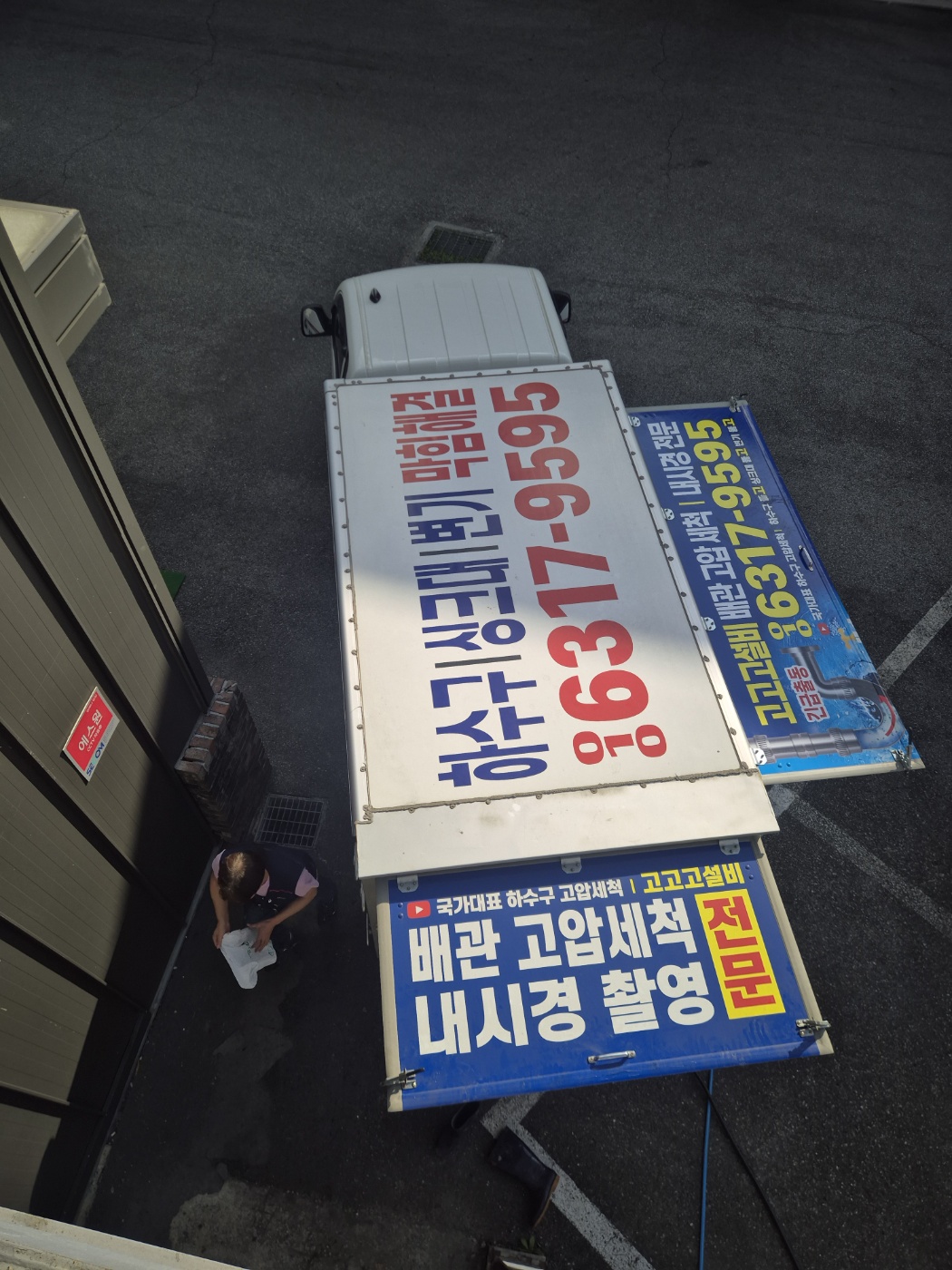 공장 건물 앞에 고압세척 장비 차량을 세우고 작업을 준비하는 사진