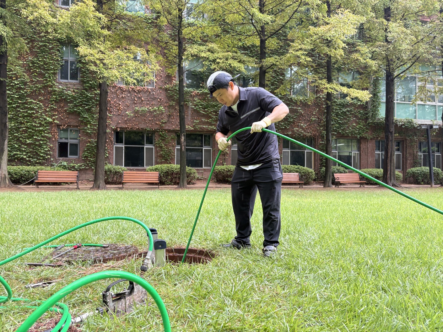 평택시 용이동 대학교 캠퍼스 잔디밭 맨홀에 고압호스를 투입하는 사진